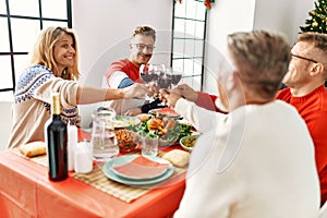 Group of middle age people smiling happy having christmas dinner toasting with wine at home