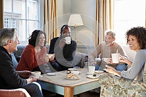 Group Of Middle Aged Friends Meeting Around Table In Coffee Shop