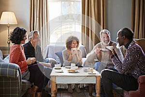 Group Of Middle Aged Friends Meeting Around Table In Coffee Shop