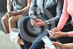 Group of millennial business people using mobile phones and sitting on couch. Networking and teamwork. Working on project.