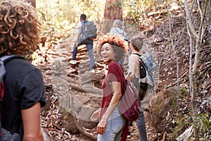 Group of millennial  friends hiking uphill on a forest trail, three quarter length photo