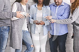 Group of millennials reaching hands to cellphone photo