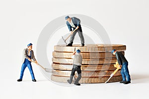 Group of miner figurines with equipment working on stack of bitcoins