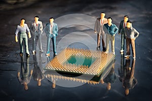 Group of miniature model of businessmen standing around the cpu in a reflective surface.