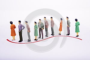 Group of miniature people over white background standing in line