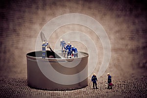 Group of miniature workers opening a can. Color tone tuned macro