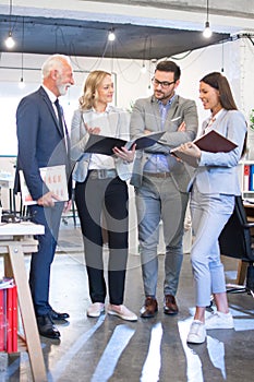 Group of mixed age business people analyzing documents together on meeting in office.