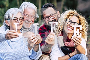 Group of mixed ages generations people smiling and showing blocks letters with  life word -  happy lifestye enjoying the outdoor photo