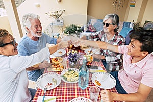 Group of mixed generations people have fun together during lunch at home in outdoor terrae - cheerful men and women from. old to