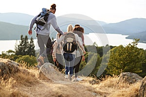 A group of mixed race young adult friends descending after a mountain hike, back view