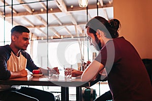 Group of mixed race young men talking and laughing in lounge bar. Multiracial friends having fun in cafe. Guys hangout