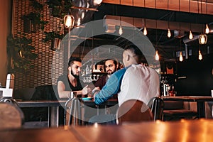 Group of mixed race young men talking in lounge bar. Multiracial friends hanging out and having fun in cafe
