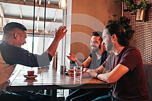 Group of mixed race young men talking in lounge bar. Multiracial friends having fun in cafe