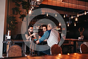 Group of mixed race young men talking in lounge bar. Multiracial friends having fun in cafe