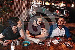 Group of mixed race young men talking in lounge bar. Multiracial friends having fun in cafe