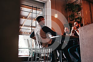 Group of mixed race young men talking in lounge bar. Multiracial friends having fun in cafe