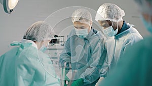 Group of mixed-races professional surgeons and nurses in uniform performing heart transplant surgery