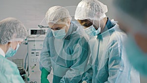 Group of mixed-races professional surgeons and nurses in uniform performing heart transplant surgery operation