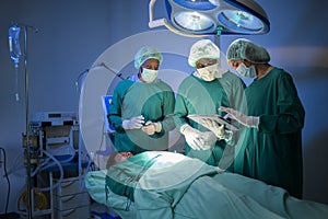 Group of mixed-races professional surgeons operating in hospital operating room , health care concept