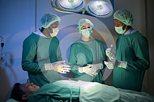 Group of mixed-races professional surgeons operating in hospital operating room , health care concept