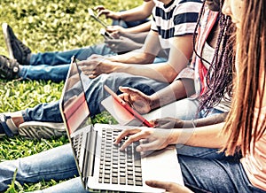 Group of mixed races teenagers using laptops and smartphones out photo