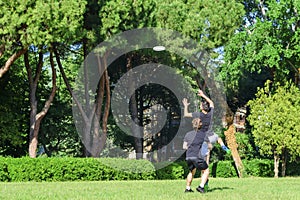 Group of mixed young teenagers people in casual wear playing with plastic flying disc game in a park oudoors. jumping man catch a