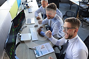 Group of modern business men in formalwear analyzing stock market data while working in the office