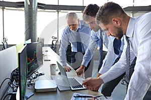 Group of modern business men in formalwear analyzing stock market data while working in the office