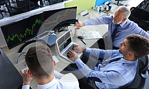 Group of modern business men in formalwear analyzing stock market data while working in the office