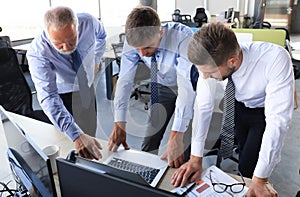 Group of modern business men in formalwear analyzing stock market data while working in the office