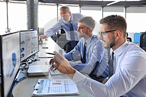 Group of modern business men in formalwear analyzing stock market data while working in the office