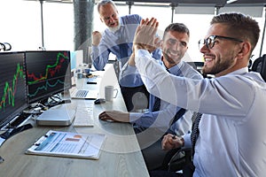 Group of modern business men in formalwear smiling and gesturing while working in the office