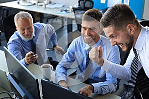 Group of modern business men in formalwear smiling and gesturing while working in the office