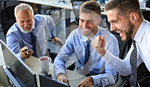 Group of modern business men in formalwear smiling and gesturing while working in the office