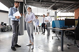 Group of modern business people are talking and smiling while standing in the office hallway