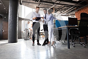 Group of modern business people are talking and smiling while standing in the office hallway