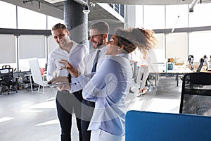 Group of modern business people are talking and smiling while standing in the office hallway