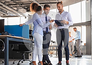 Group of modern business people are talking and smiling while standing in the office hallway