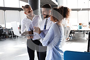 Group of modern business people are working using laptop and smiling while standing in the office hallway