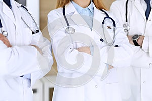 Group of modern doctors standing as a team with arms crossed in hospital office, close-up. Physicians ready to examine