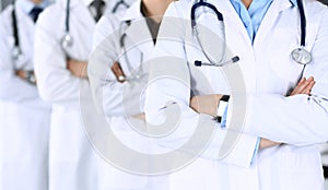 Group of modern doctors standing as a team with arms crossed in hospital office. Physicians ready to examine and help