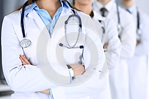 Group of modern doctors standing as a team with arms crossed in hospital office. Physicians ready to examine and help