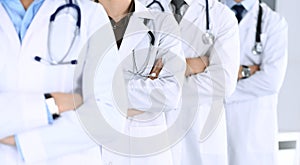 Group of modern doctors standing as a team with arms crossed in hospital office. Physicians ready to examine and help