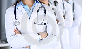 Group of modern doctors standing as a team with arms crossed in hospital office. Physicians ready to examine and help