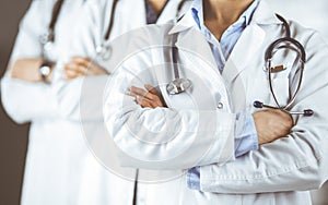 Group of modern doctors standing as a team with arms crossed in hospital office and ready to help patients. Medical help