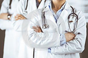 Group of modern doctors standing as a team with arms crossed in hospital office and ready to help patients. Medical help