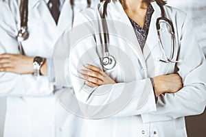 Group of modern doctors standing as a team with arms crossed in hospital office and ready to help patients. Medical help