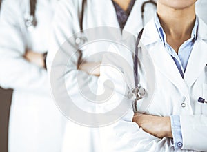 Group of modern doctors standing as a team with arms crossed in hospital office and ready to help patients. Medical help