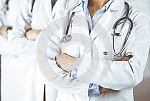 Group of modern doctors standing as a team with arms crossed in hospital office and ready to help patients. Medical help