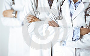 Group of modern doctors standing as a team with arms crossed in hospital office and ready to help patients. Medical help